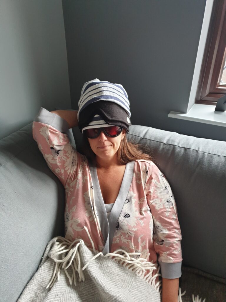 Laura Hunter, Evesham Therapist, sitting on a sofa with a cold-pack on her head, suffering with a migraine