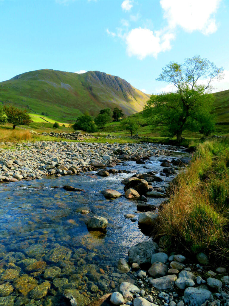 Babbling stream with a rocky shore and mountain in the background with blue sky above